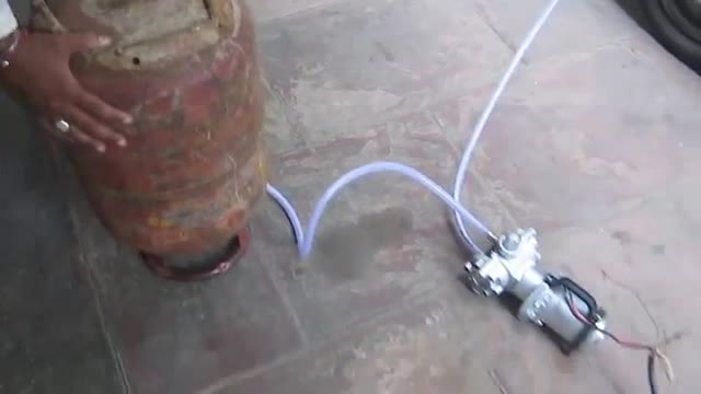 The 12V pump connected to a gas cylinder, filling a car